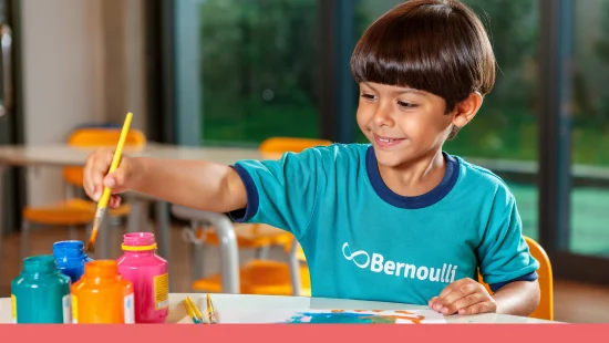 Aluno de 4 anos do Colégio Bernoulli pintando na mesa da escola