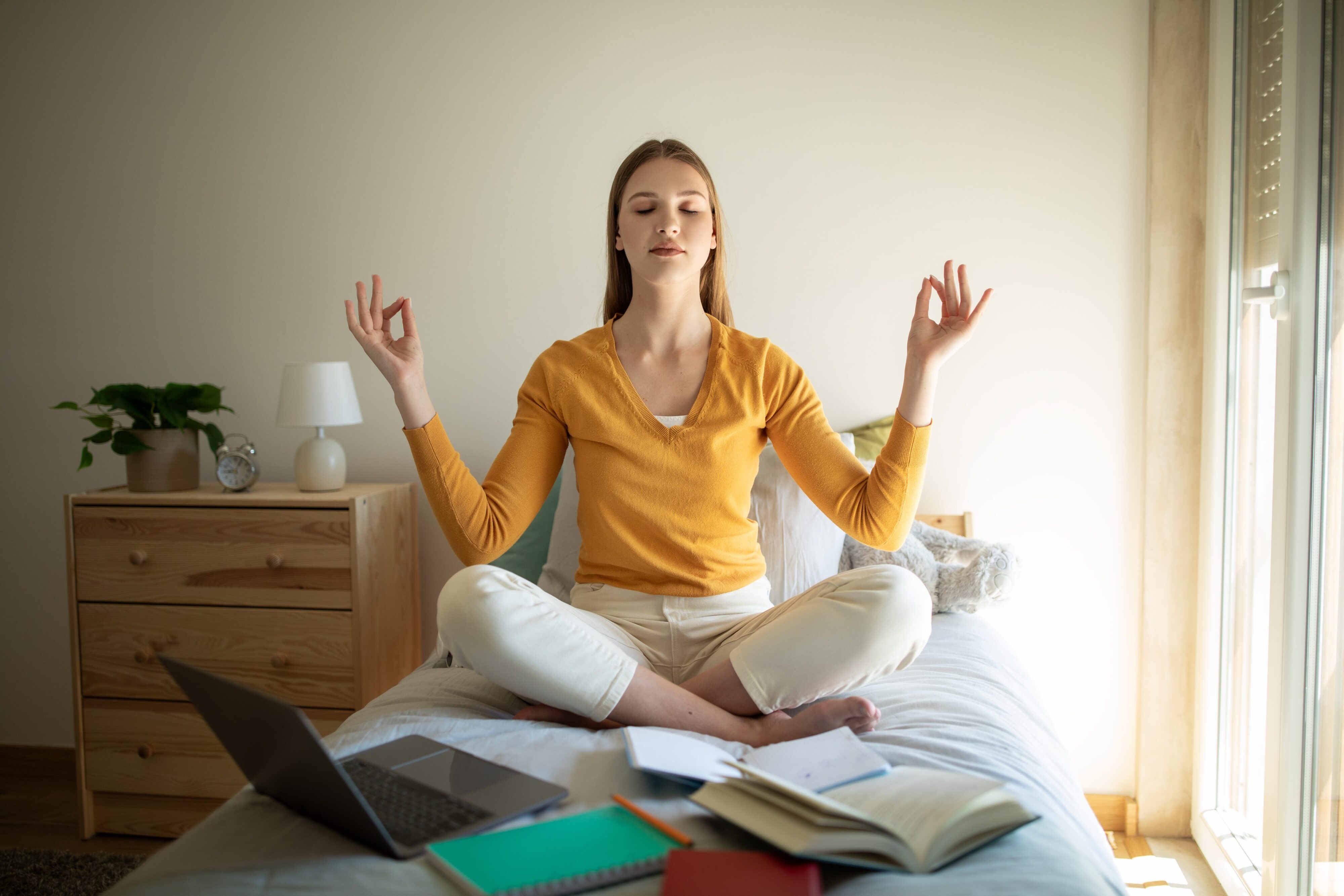 Jovem mulher fazendo uma pausa com meditação durante os estudos.